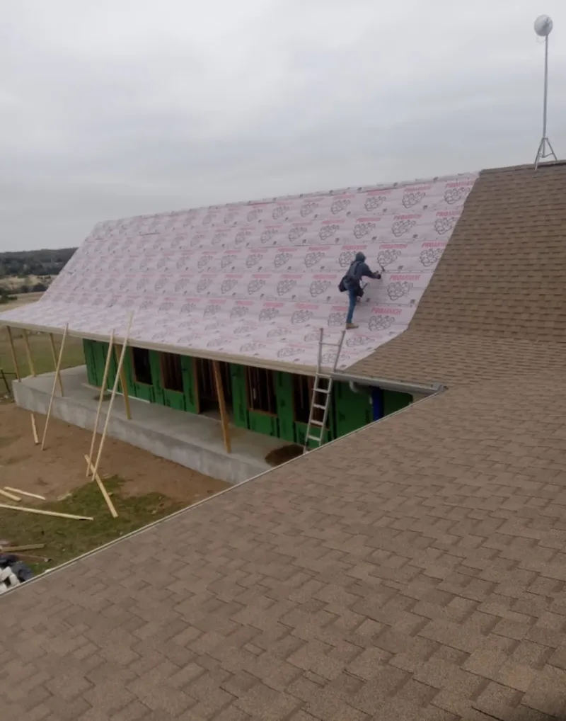 Worker preparing underlayment for a metal roof installation in Cambria